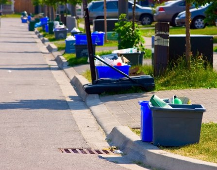 Operative placing a skip at a residential driveway illustrating insured skip hire services